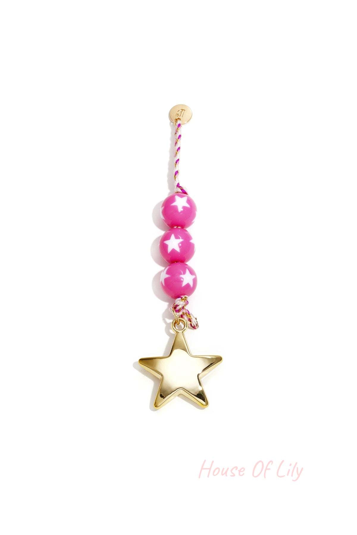 Close-up of bright pink star patterned bead charm with gold star pendant and braided cord