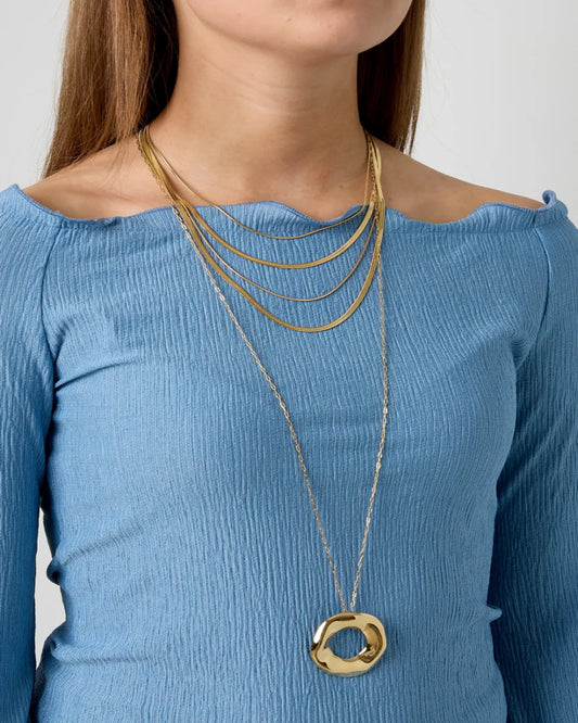 Woman wearing a blue off-shoulder top with gold necklaces