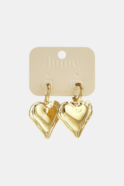 Chunky gold heart hoop earrings displayed on a beige Lumé branded jewelry card
