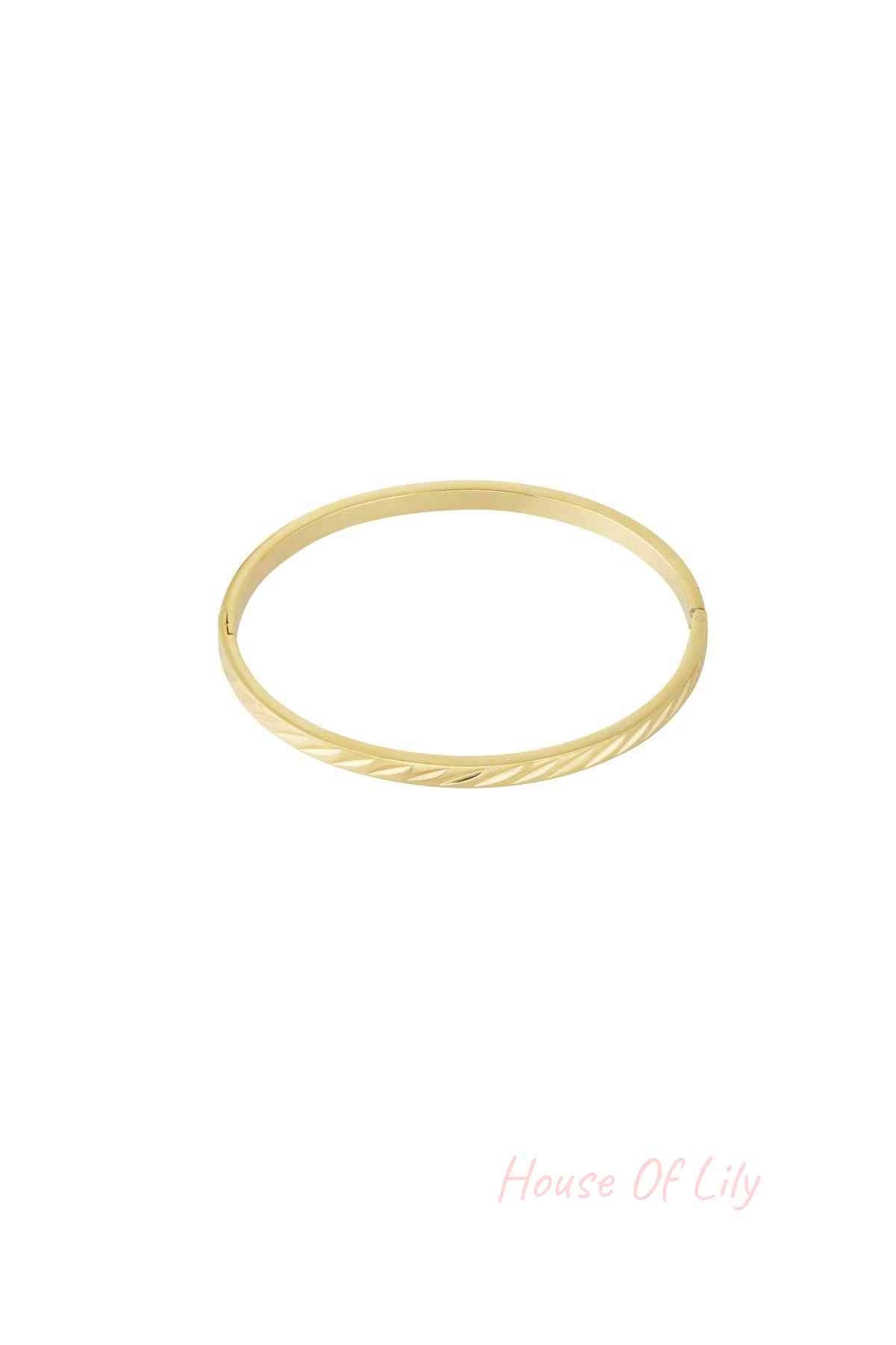 Gold-tone minimal twist metal bangle with hinged clasp on white background