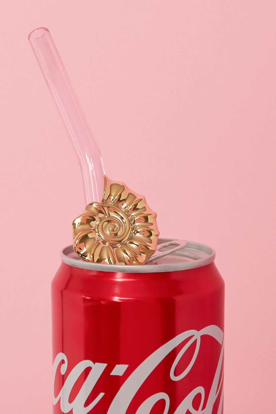 Gold spiral shell ring displayed on a clear straw atop a red soda can with a pink background
