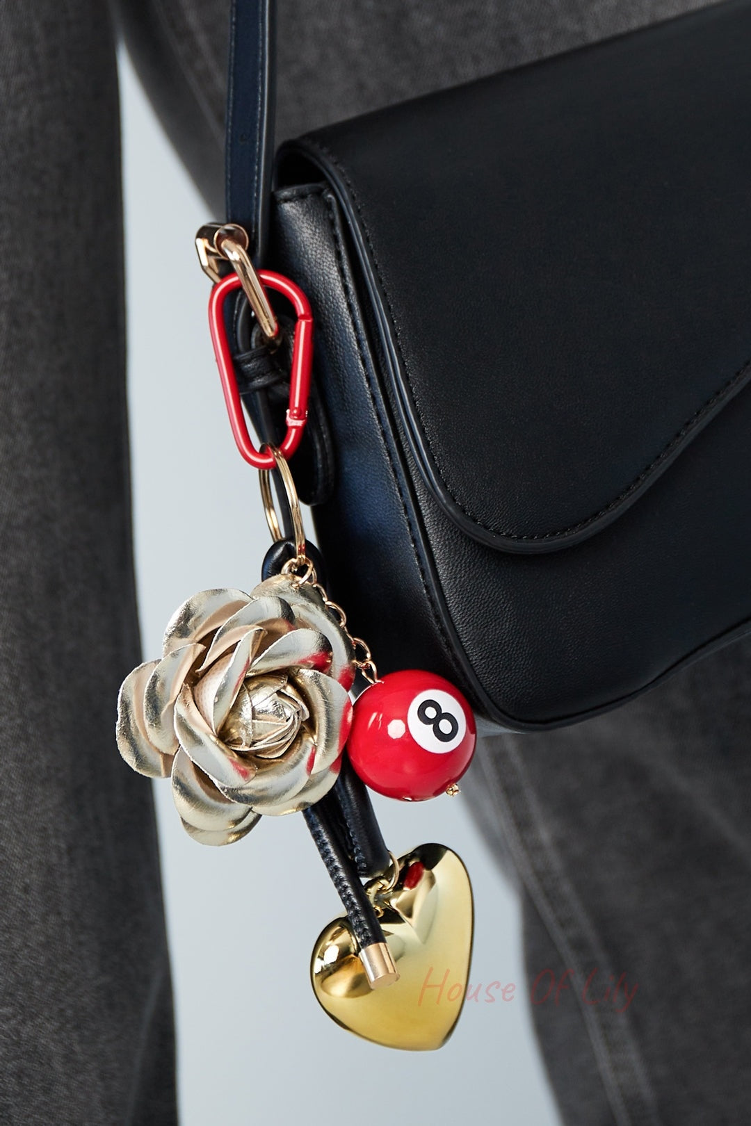 Lifestyle shot of the charm attached to a black leather crossbody bag showing its size and playful look