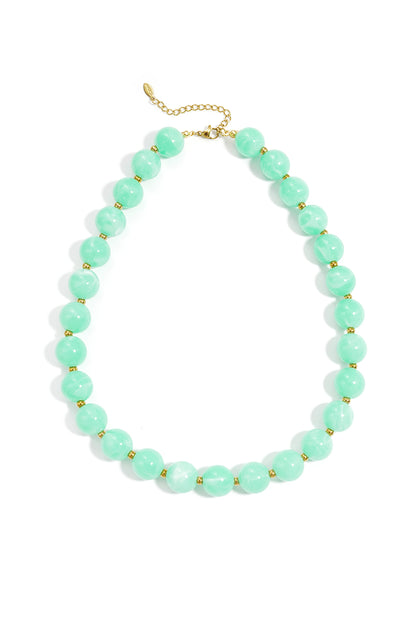 A statement necklace featuring large, round, mint green marbled beads separated by small gold spacers on a gold chain.