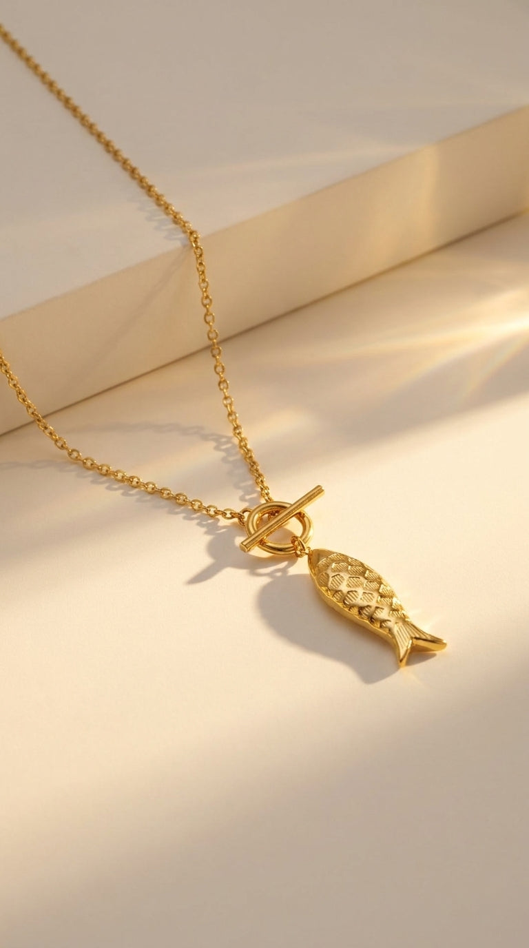 Gold Catching Vibes necklace with a textured fish charm and a toggle clasp on a delicate chain.