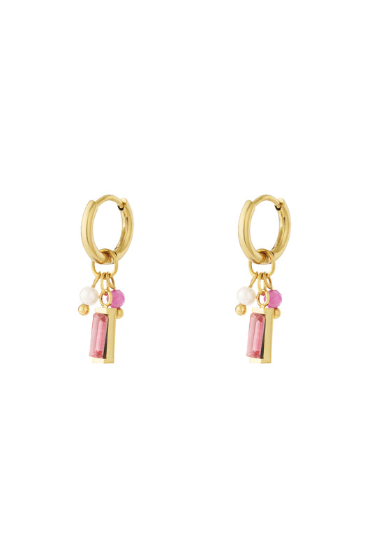 Pair of gold hoop earrings with pink rectangular gemstone, pearl, and pink bead charms on white background