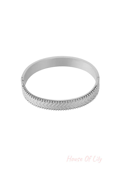 Silver chevron patterned bangle bracelet with beaded edges on white background