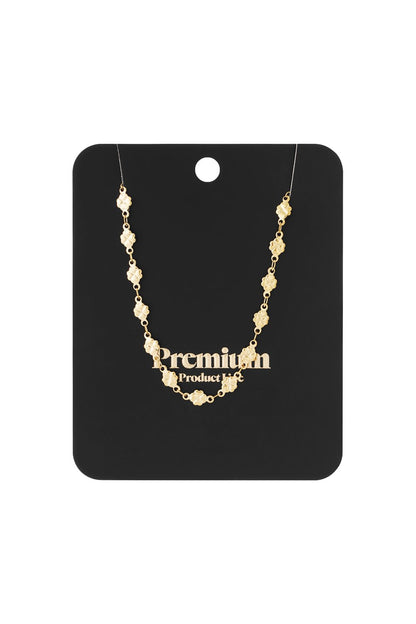 Gold-tone chain necklace featuring small, repeating four-leaf clover charms on a black display card.