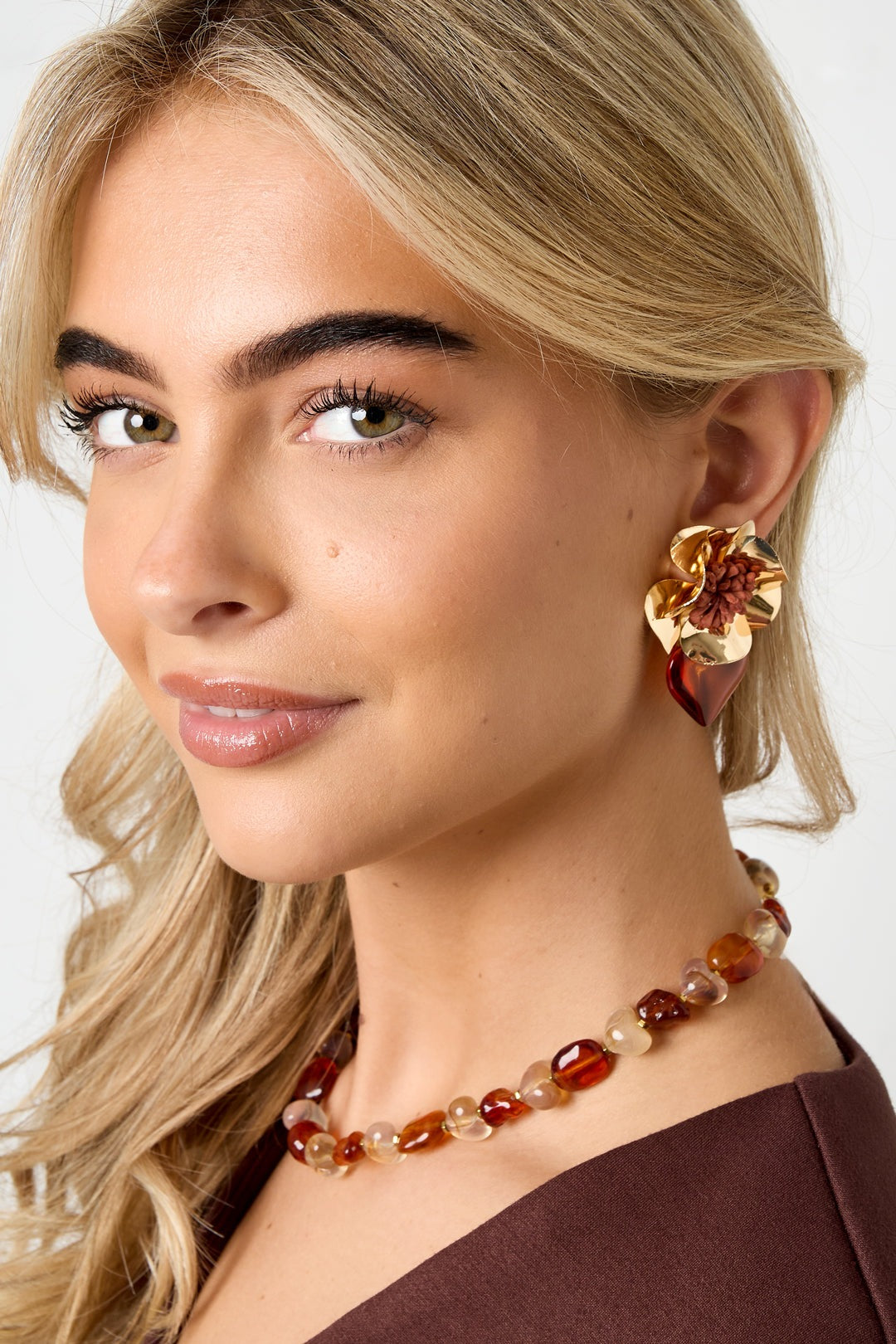 Model wearing red floral heart drop earring showcasing bold and playful design with gold and fabric details