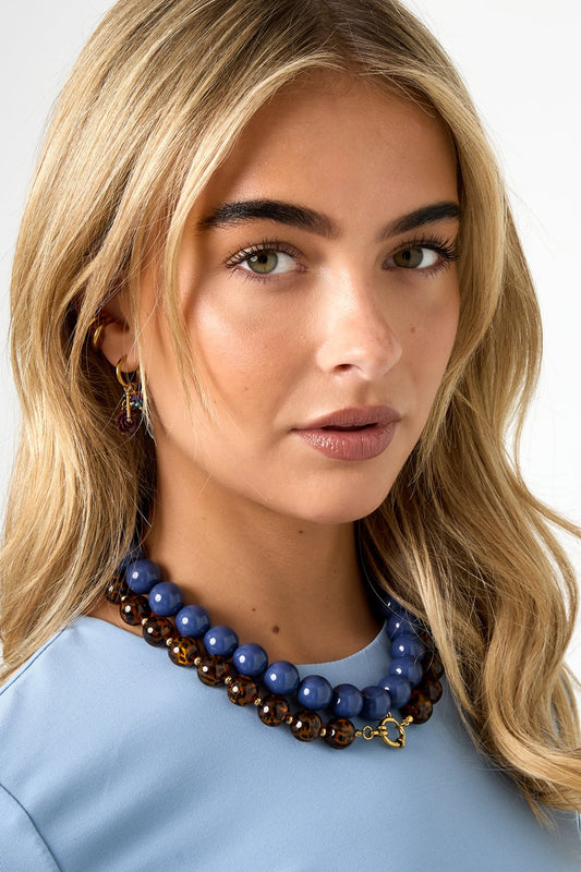 Close-up of model wearing olive green chunky bead necklace over black top