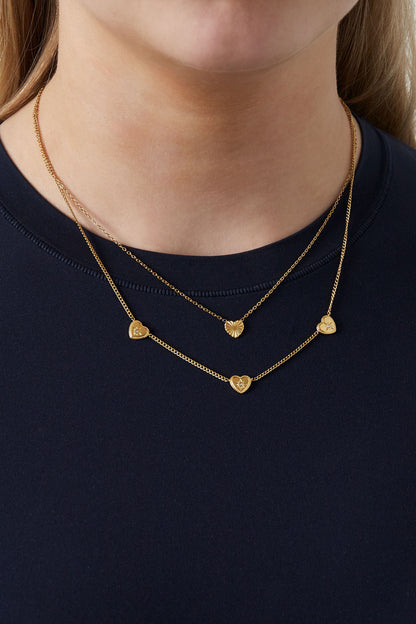 Close-up image showing the necklace worn on a woman’s neck layered over a black top