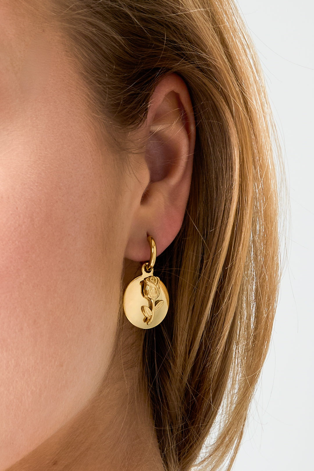 Main Character Rose Drops: A gold hoop earring with a round coin pendant featuring an embossed rose design.