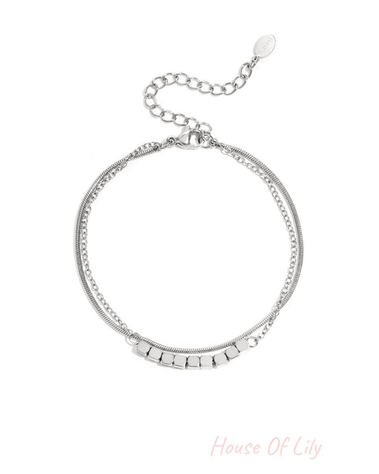Silver-toned dainty cube chain bracelet with adjustable clasp laid flat on white background