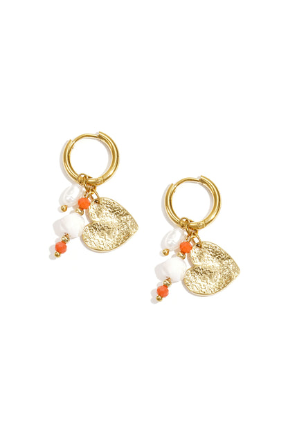 Pair of gold hoop earrings featuring hammered heart charm, pearls, and small orange and white beads on a white background