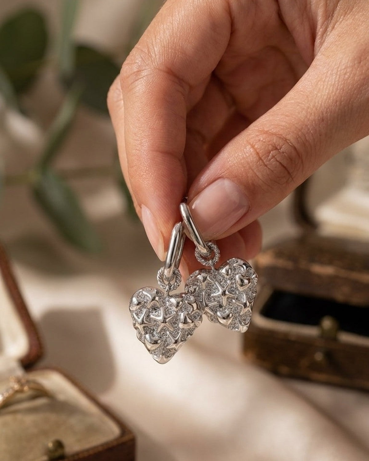 Silver squoval hoop earrings with pavé-set stones and dimensional heart and star charms.