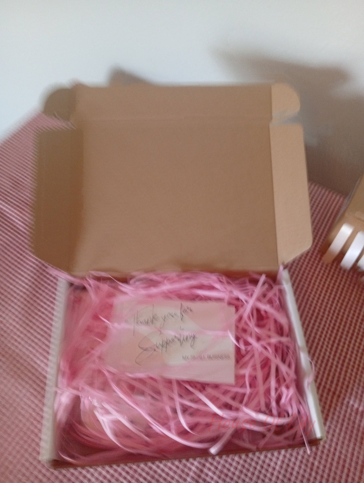 Mystery Box: Launch Edition, open brown cardboard box filled with pink crinkle paper and a thank you card.