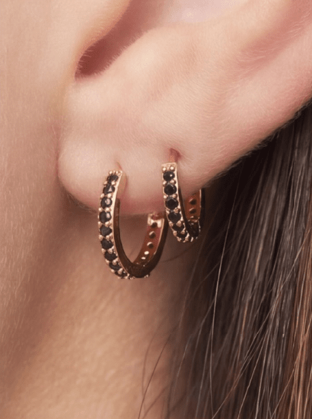 Crystal Sparkle Hoops: Gold huggie hoop earrings embedded with small, round-cut black crystals worn on an earlobe.