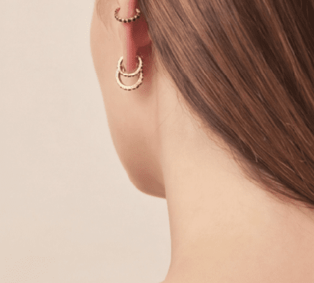 Crystal Sparkle Hoops: Gold mini hoop earrings with black stone accents, worn as a stacked set on an ear.
