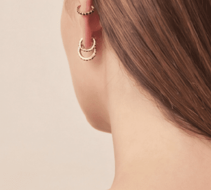 Crystal Sparkle Hoops: Gold mini hoop earrings with black stone accents, worn as a stacked set on an ear.