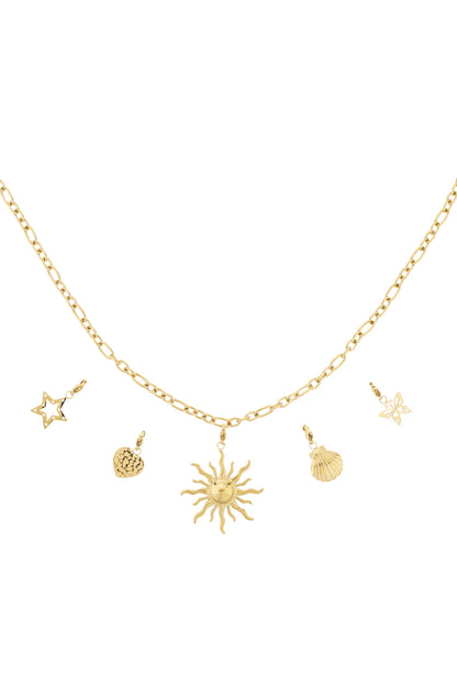 Gold chain necklace with five distinct charms including a sun, star, heart, butterfly, and seashell pendants laid out on white background