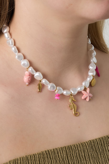Close-up of the ocean charm necklace worn by a woman, highlighting the unique seaside-themed pendants and lustrous pearls