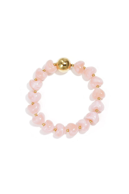 Peach heart-shaped acrylic beaded bracelet with gold bead accent on white background