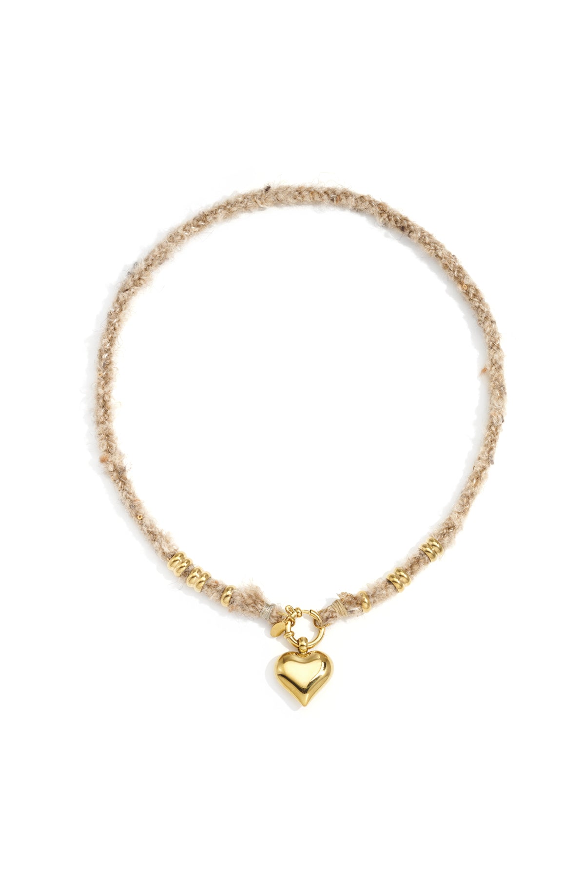 Gold heart pendant necklace with beige textured wool rope chain and gold rings laid flat on white background