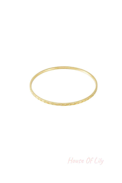 Close-up of a delicate gold bangle with rhinestone accents on white background