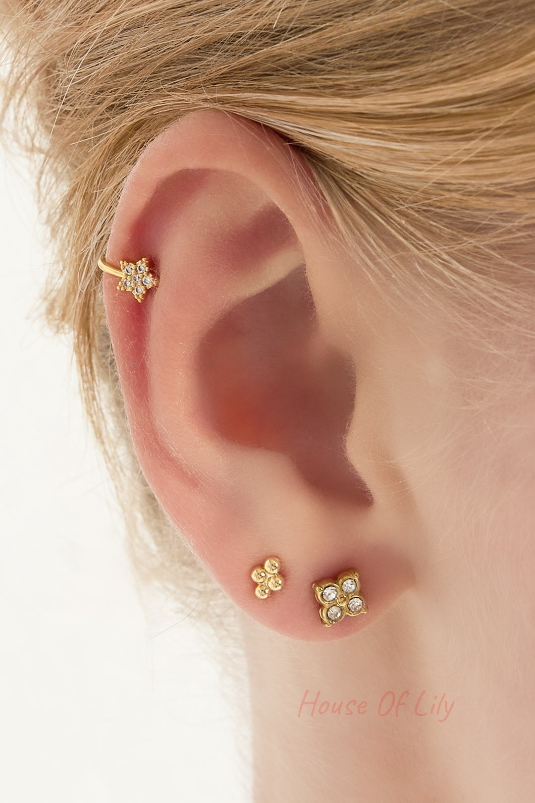 Side view of ear showing gold star ear cuff and two matching stud earrings on a woman's ear with blonde hair