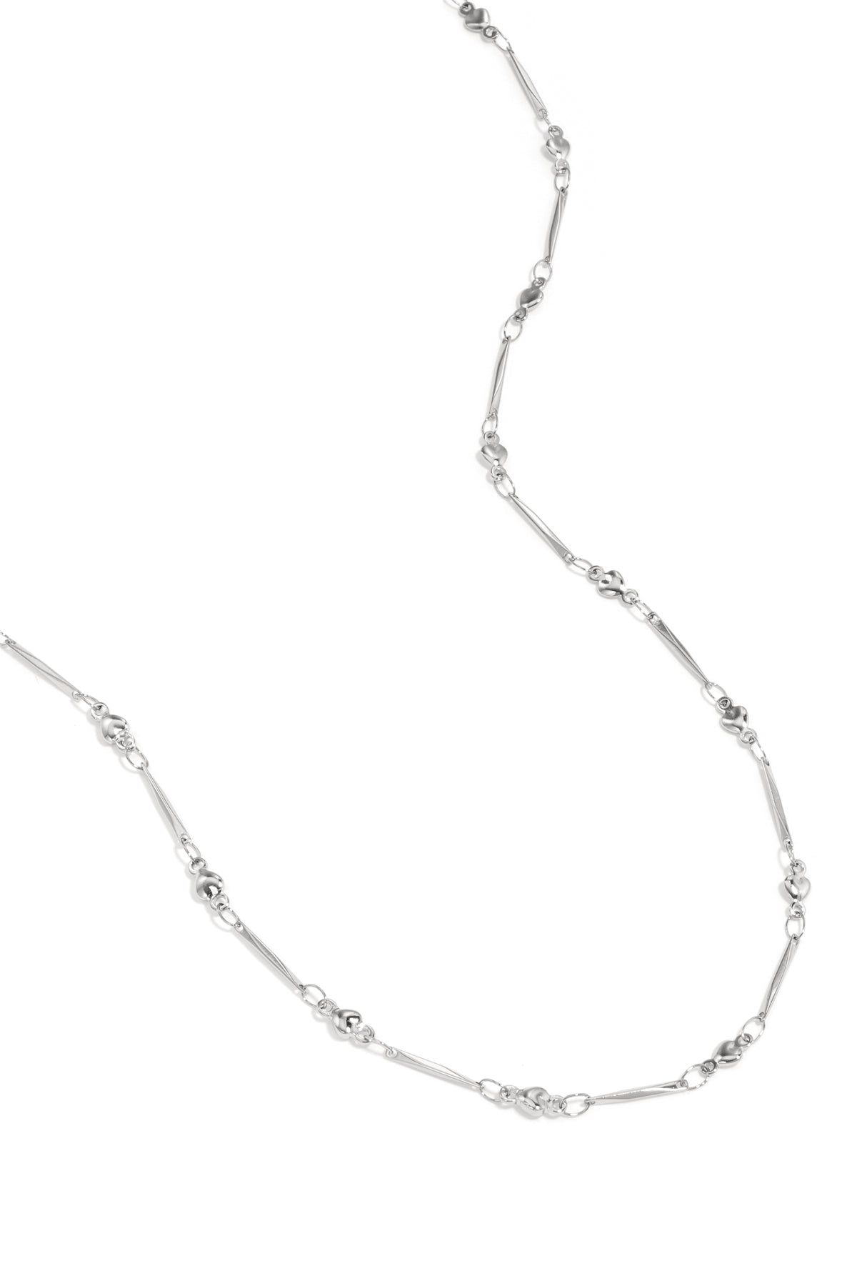 Close-up view of delicate silver necklace with alternating heart-shaped and elongated bar links on white background