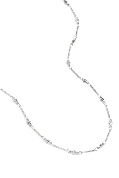 Close-up view of delicate silver necklace with alternating heart-shaped and elongated bar links on white background