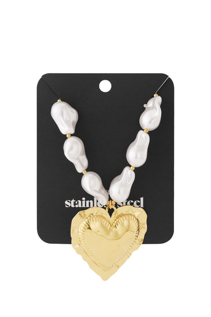 Baroque pearl necklace with a large, textured gold heart pendant on a black display card.