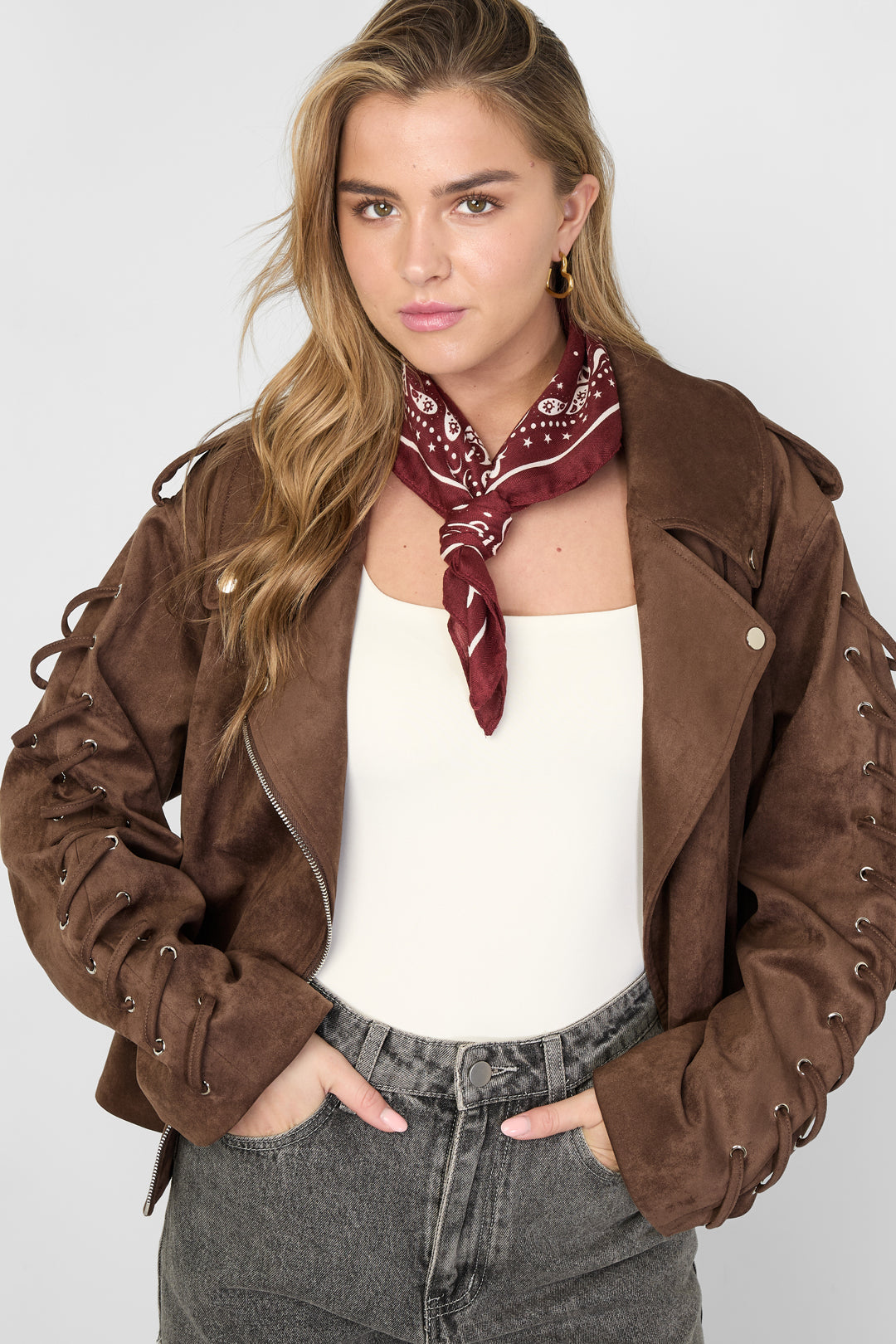 Woman wearing burgundy polka dot bandana scarf tied around her neck paired with brown jacket