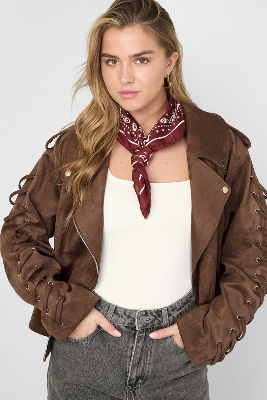 Woman wearing burgundy polka dot bandana scarf tied around her neck paired with brown jacket