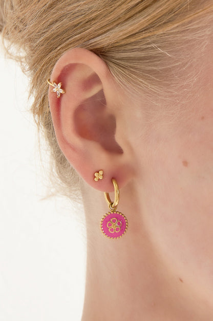 Close-up of a woman's ear wearing gold-tone hoop drop earring with bright pink enamel flower charm