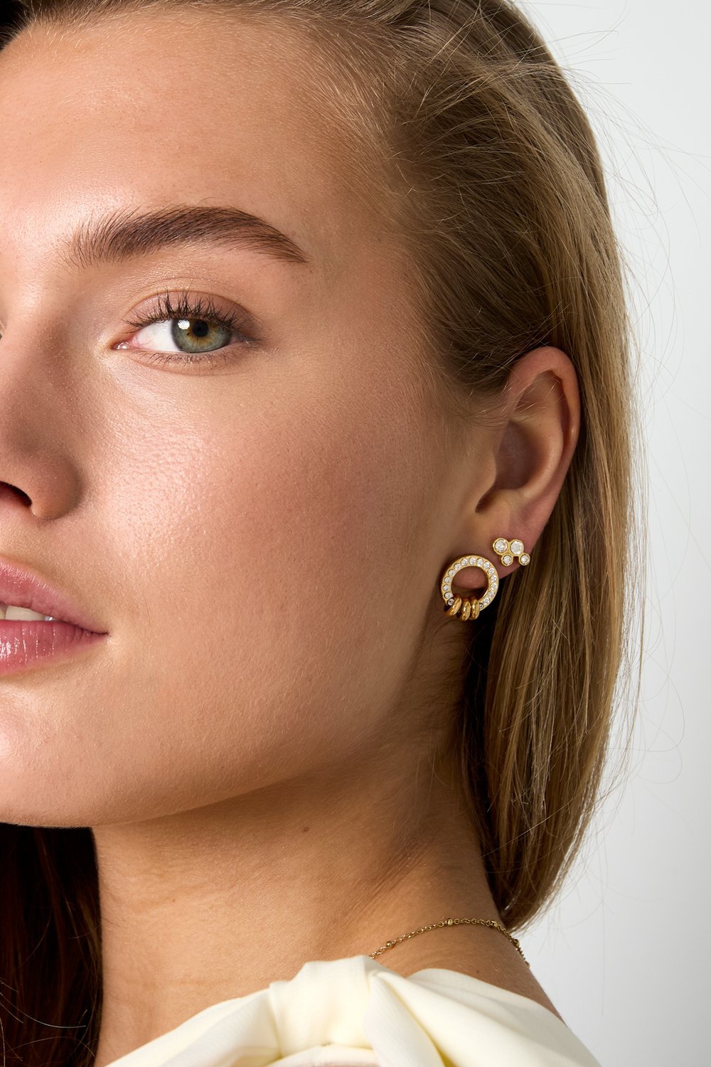 Glitch Orbit gold stud earrings featuring a pave-encrusted circle with dangling rings and a matching cluster stud.
