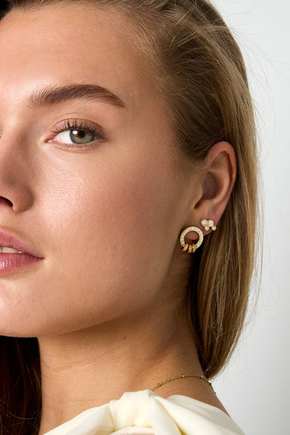 Glitch Orbit gold stud earrings featuring a pave-encrusted circle with dangling rings and a matching cluster stud.