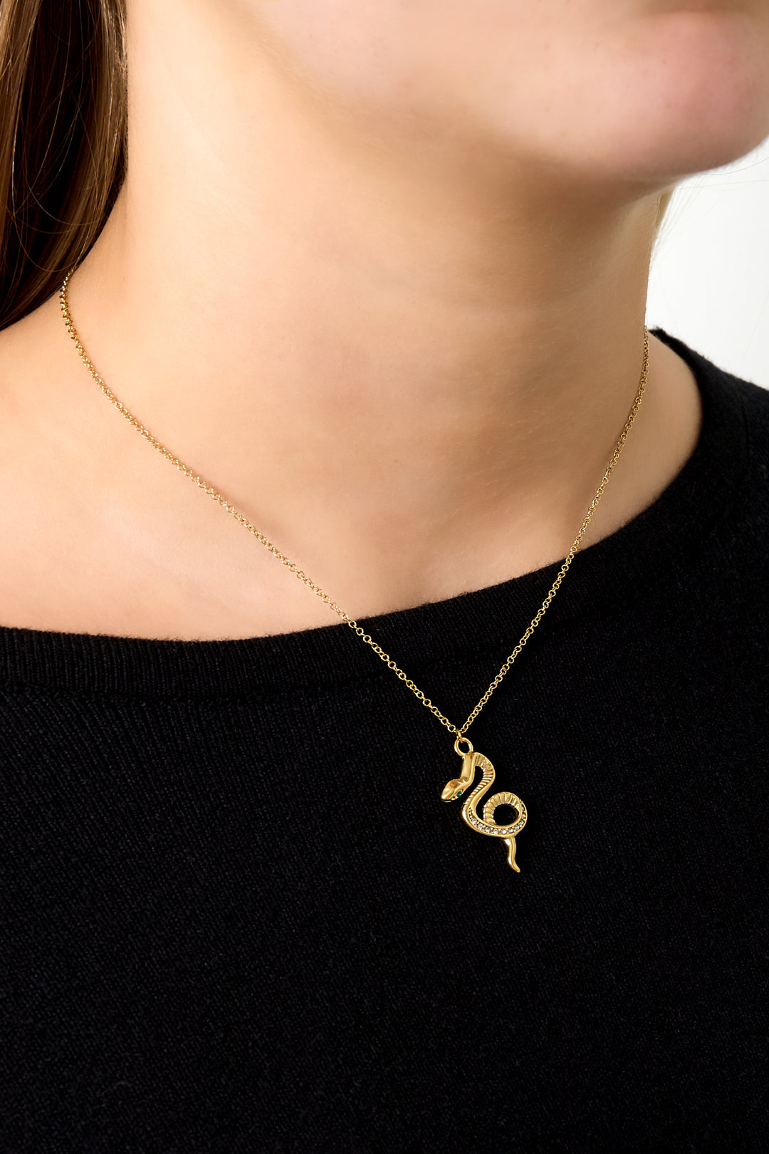 Woman wearing gold snake pendant necklace with black top