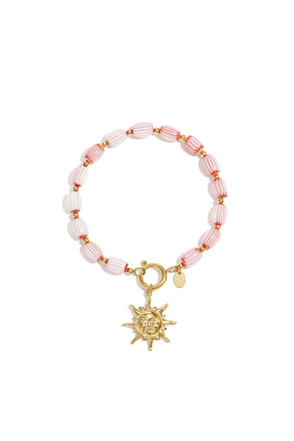 Pink and white striped beaded bracelet with gold-tone sun charm on white background