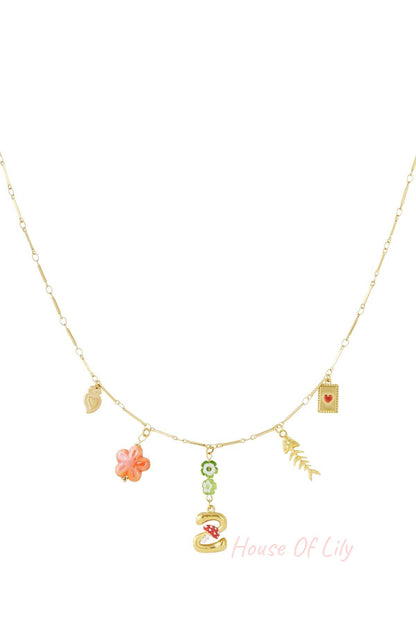 Gold chain necklace with assorted charms, including a letter initial, mushroom, flower, fish skeleton, and heart icons.