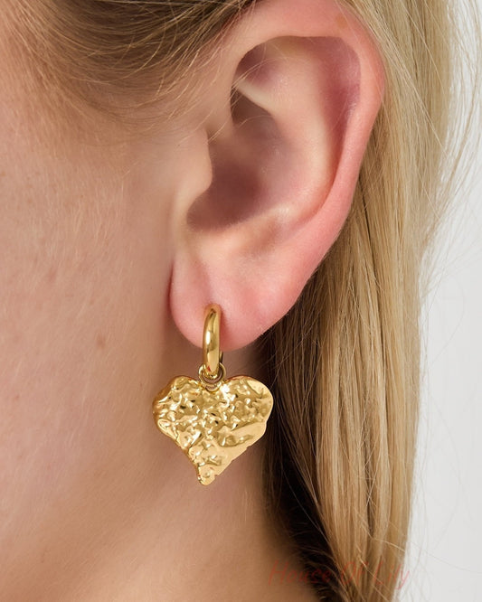 Detailed view of gold textured heart hoop earring worn on ear with smooth hoop and hammered heart charm