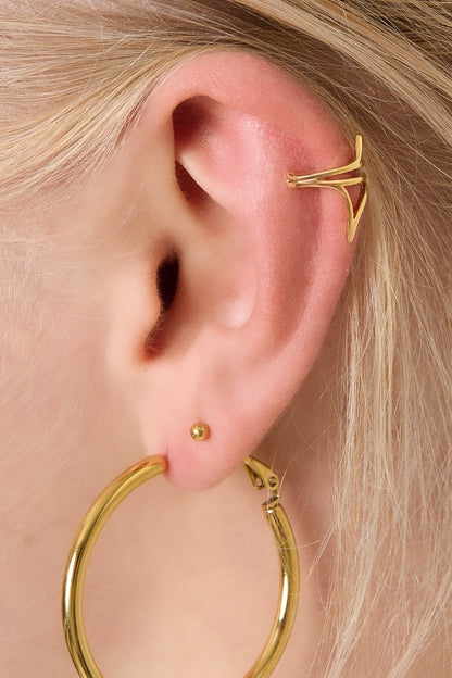 Close-up of woman's ear wearing gold geometric ear cuff with large gold hoop earring and small ball stud