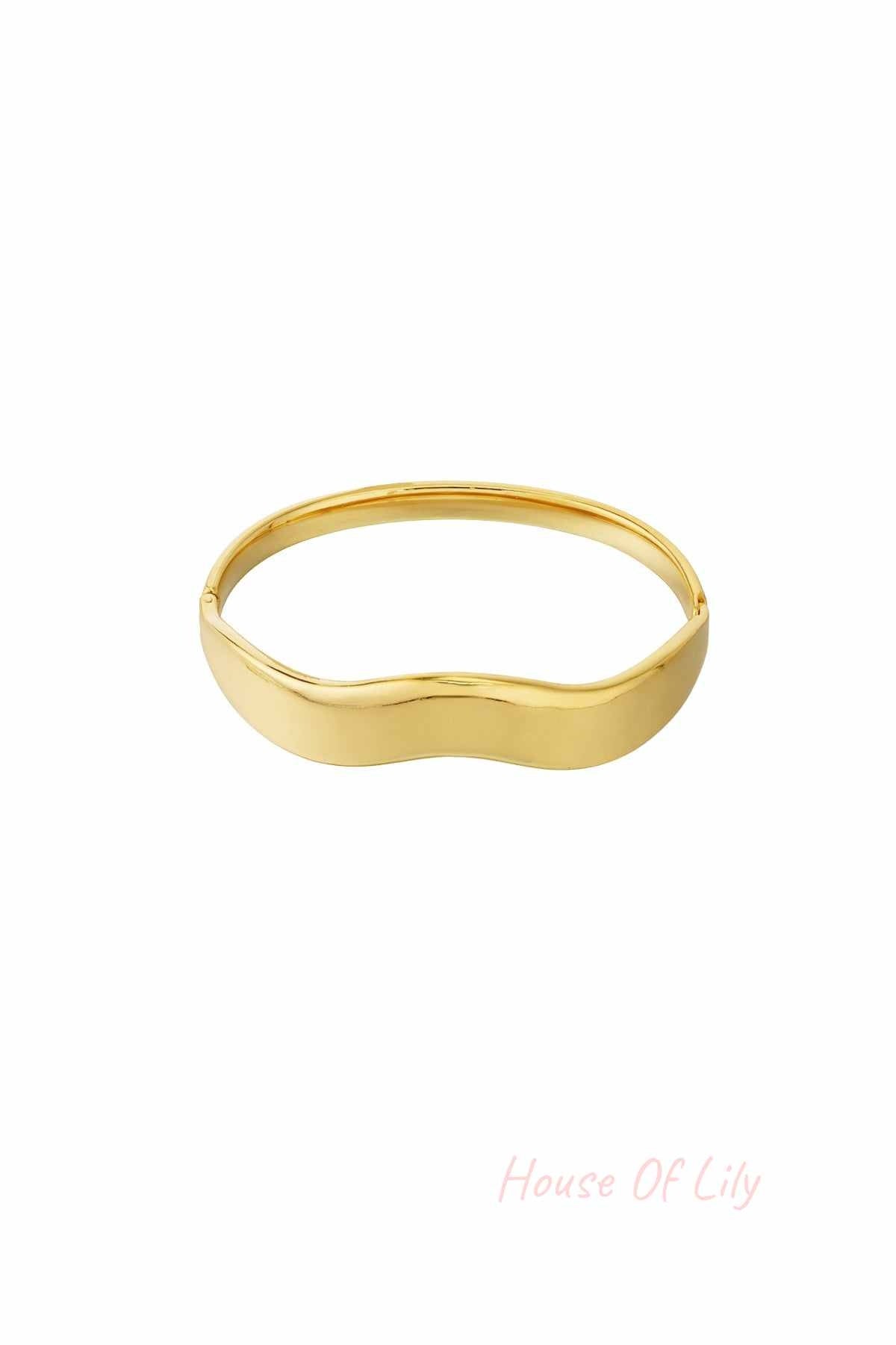 Minimalist wavy gold bangle bracelet with smooth polished surface against white background