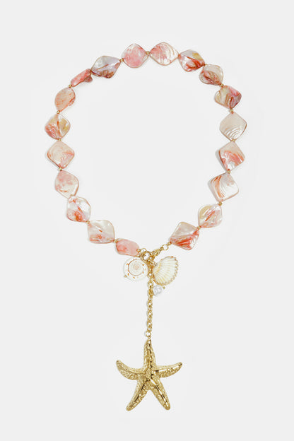 Pink and cream shell bead necklace with gold-tone starfish and shell charms laid flat on white background