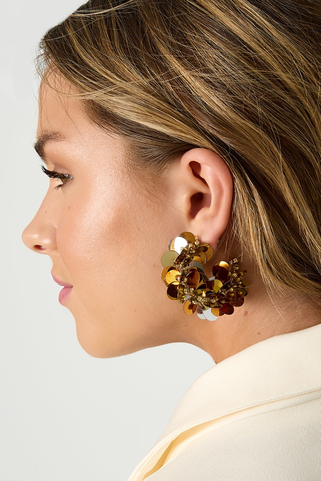 Model profile showing gold-tone sequin hoop earring with layered circular discs and beads