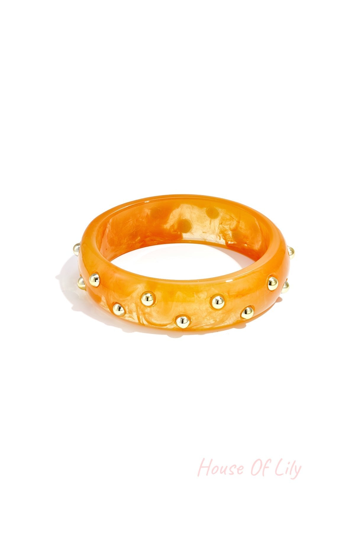Orange resin bangle with gold-tone studs on white background