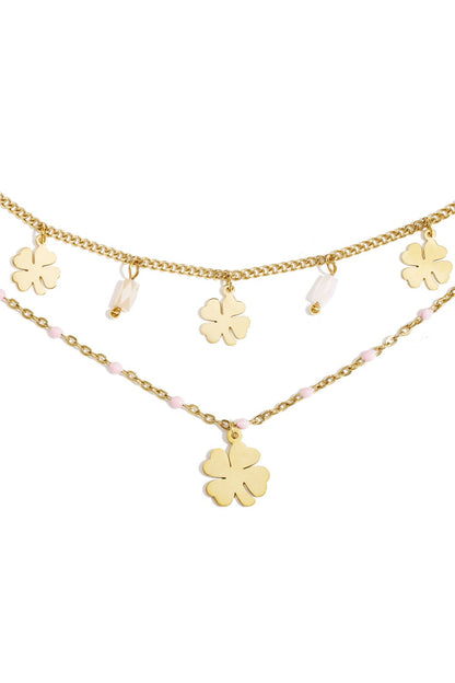 Elegant gold layered chain bracelet featuring dangling four-leaf clover charms, white beads, and small pink accents.