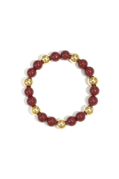 Single acrylic beaded bracelet featuring alternating cranberry red and gold-tone beads isolated on white background