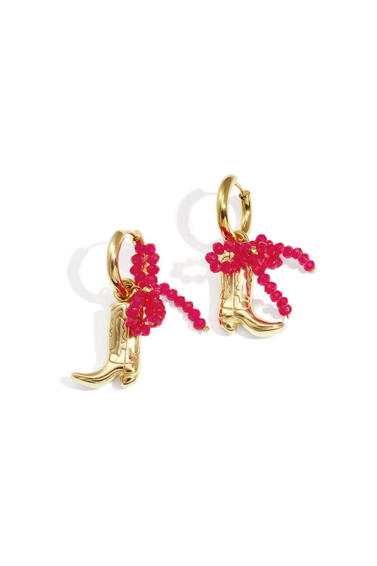 Gold-tone cowboy boot drop earrings with a bright pink beaded bow detail