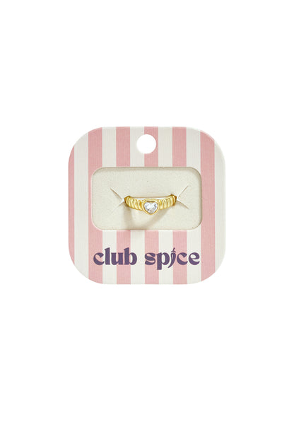 Gold-toned ring with a ribbed band and a small heart-shaped crystal, mounted on a striped pink and white display card.