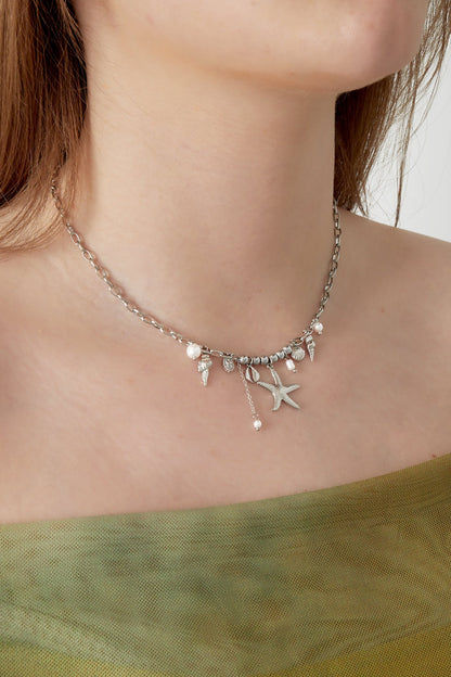 Model wearing the silver-tone seaside charm necklace styled with green outfit close-up